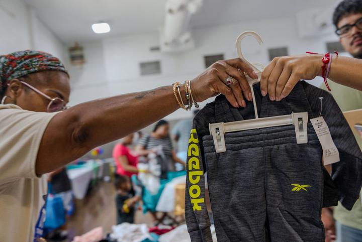 A volunteer holding up an outfit from the clothing tables